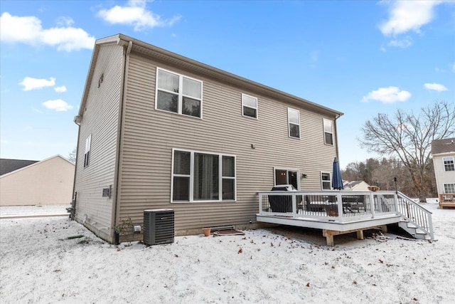 snow covered property with central AC and a deck