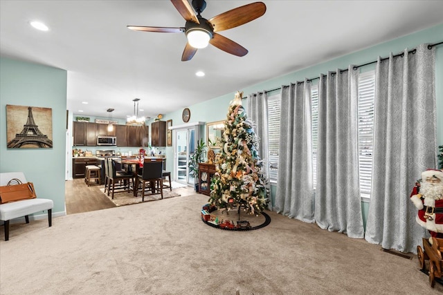 interior space featuring ceiling fan with notable chandelier and light colored carpet