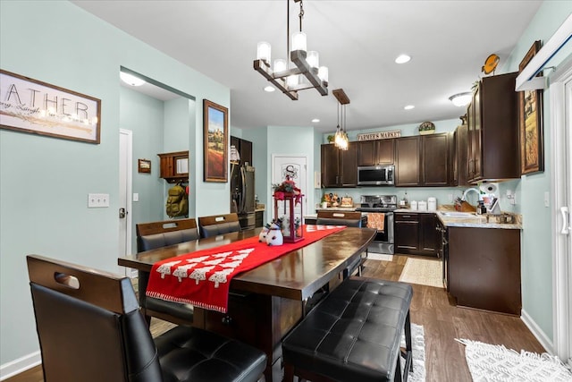 dining room with dark hardwood / wood-style flooring, a notable chandelier, and sink