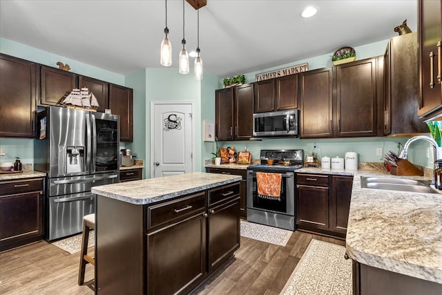 kitchen featuring dark brown cabinets, stainless steel appliances, sink, wood-type flooring, and a kitchen island