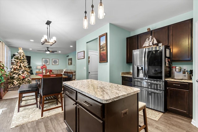 kitchen with ceiling fan with notable chandelier, hanging light fixtures, a kitchen island, light hardwood / wood-style floors, and stainless steel fridge with ice dispenser