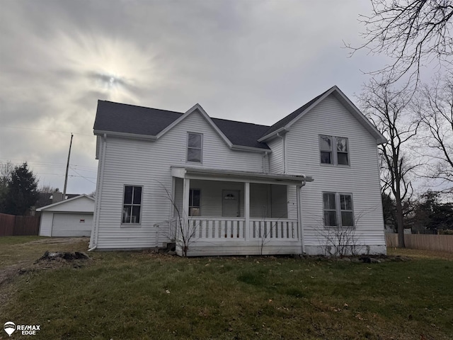 view of front facade with an outbuilding, covered porch, a front yard, and a garage