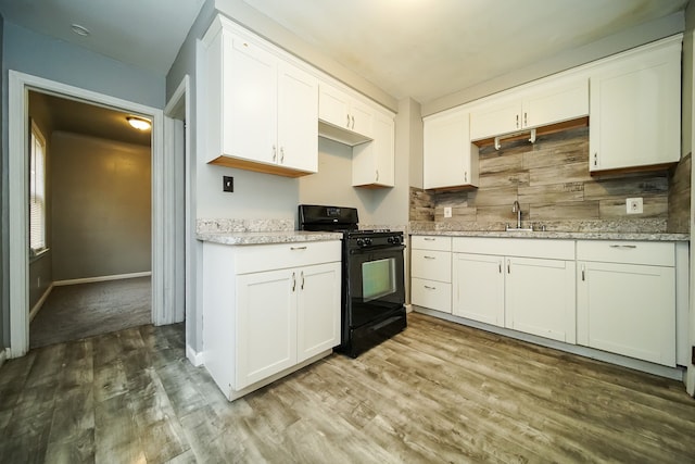 kitchen with decorative backsplash, black range with gas stovetop, sink, wood-type flooring, and white cabinetry