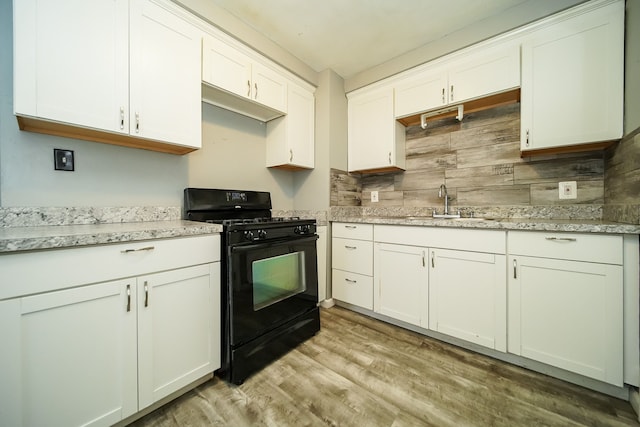 kitchen featuring decorative backsplash, light hardwood / wood-style floors, black range with gas stovetop, and white cabinetry