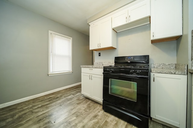 kitchen featuring white cabinets, black gas range, light wood-type flooring, and light stone countertops