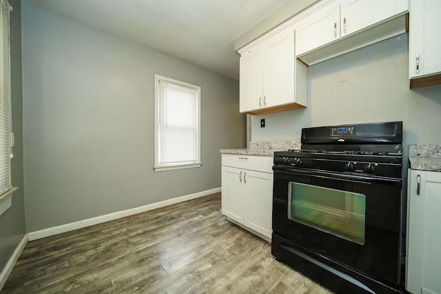 kitchen featuring black gas range, light wood-type flooring, and white cabinetry