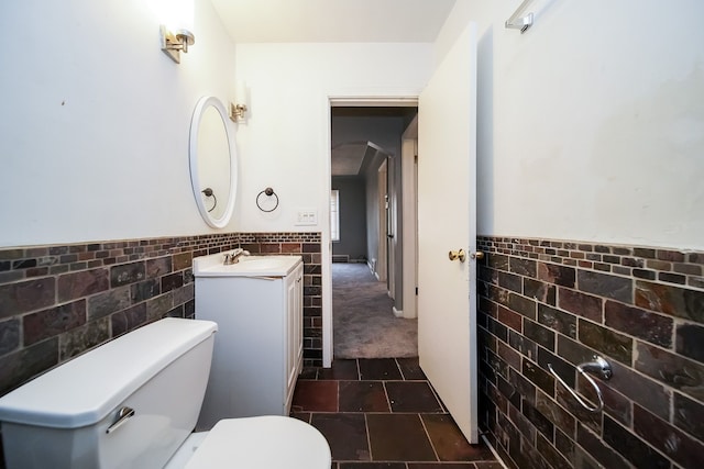 bathroom with vanity, toilet, and tile walls