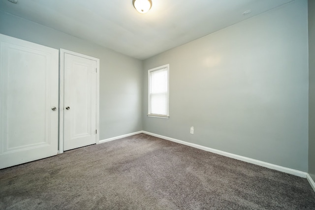 unfurnished bedroom with a closet and dark colored carpet