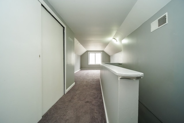 hall with dark colored carpet and lofted ceiling