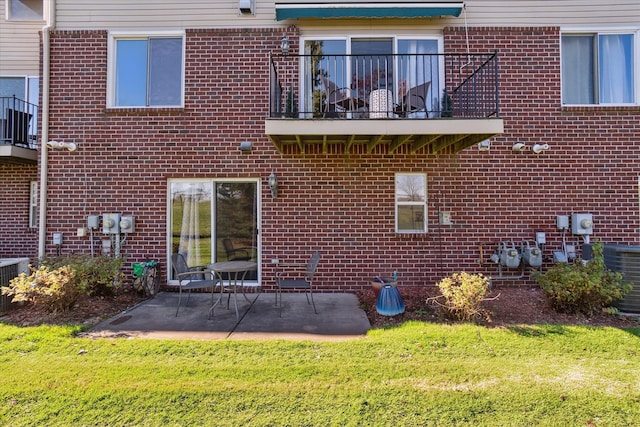 back of house featuring a patio area, brick siding, a yard, and a balcony