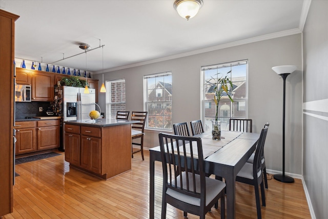 dining room with light wood finished floors, baseboards, and crown molding