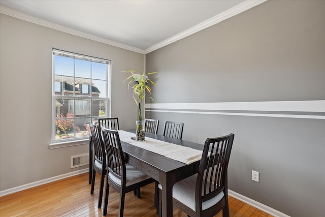 dining space with baseboards, visible vents, and light wood finished floors