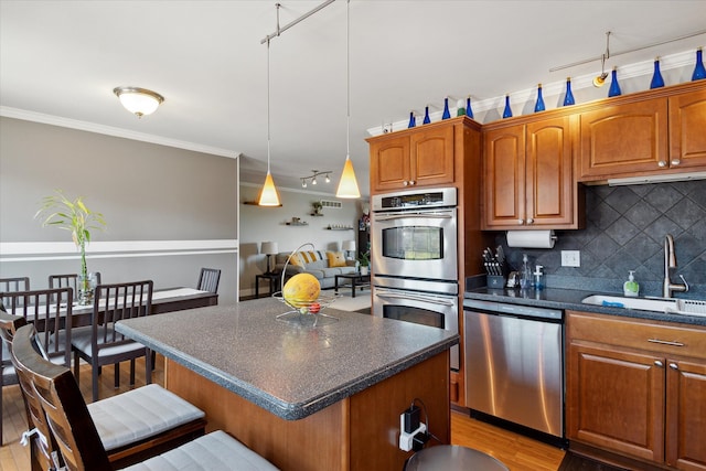 kitchen featuring tasteful backsplash, appliances with stainless steel finishes, a breakfast bar, ornamental molding, and a sink