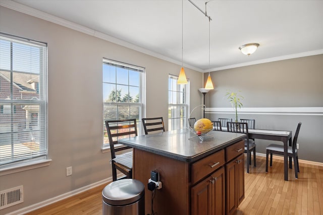 kitchen with light wood-type flooring, dark countertops, visible vents, and baseboards