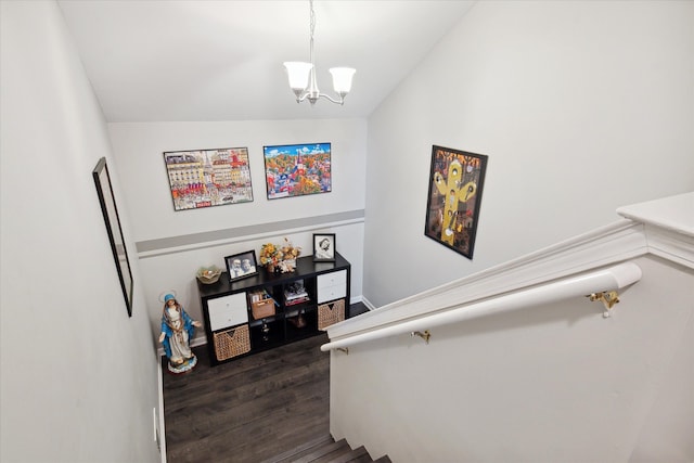 staircase featuring a chandelier, wood finished floors, and lofted ceiling