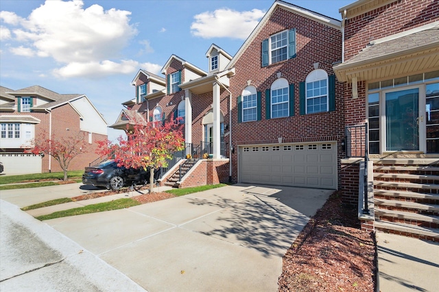 view of front of home featuring a garage, driveway, brick siding, and a residential view