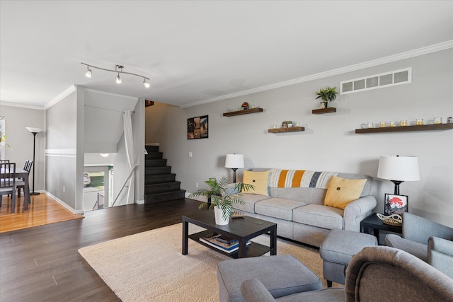 living area featuring wood finished floors, visible vents, baseboards, stairs, and ornamental molding