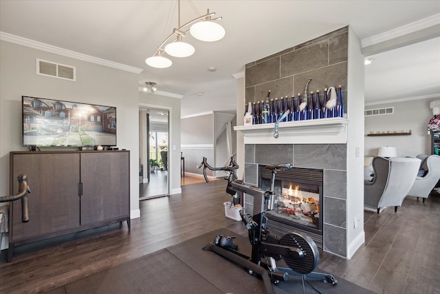 exercise room with visible vents, crown molding, a fireplace, and wood finished floors