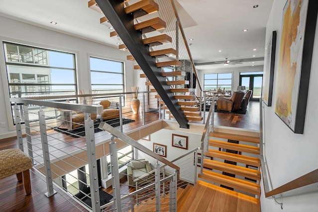 staircase featuring a wealth of natural light, hardwood / wood-style floors, and ceiling fan