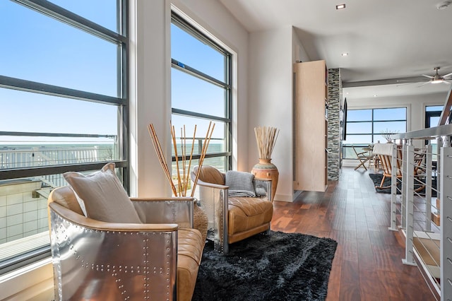 living area featuring dark hardwood / wood-style flooring, a water view, and ceiling fan