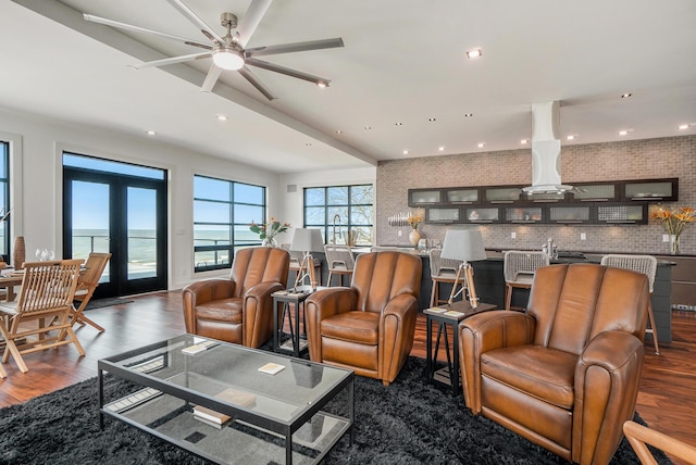 living room featuring dark hardwood / wood-style floors, ceiling fan, a water view, and french doors