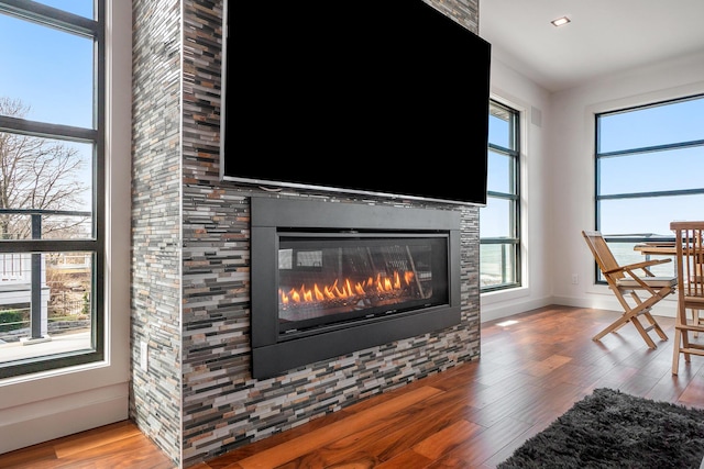 living room featuring a tile fireplace, a wealth of natural light, and hardwood / wood-style floors