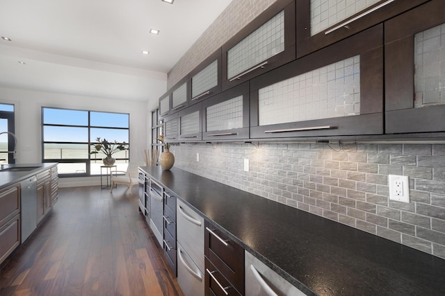 kitchen with dark brown cabinetry, dishwasher, sink, dark wood-type flooring, and decorative backsplash