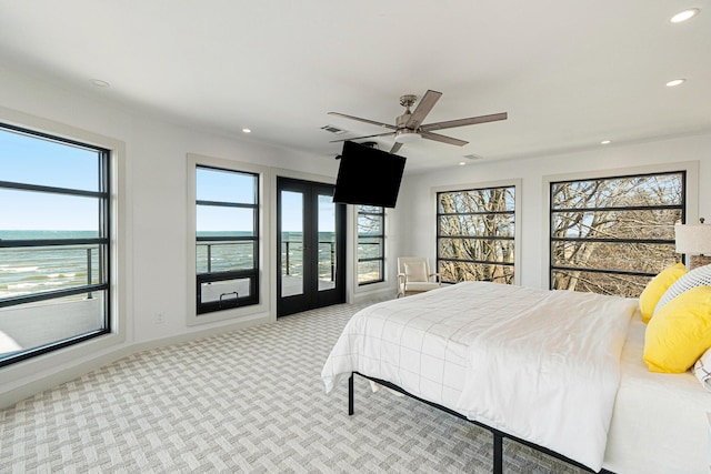 bedroom with a water view, ceiling fan, and light colored carpet