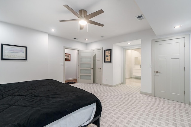 bedroom featuring ceiling fan, light colored carpet, and connected bathroom