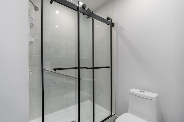 bathroom featuring a shower with shower door and toilet