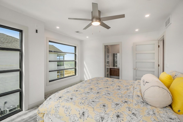 bedroom featuring ceiling fan, light wood-type flooring, connected bathroom, and multiple windows