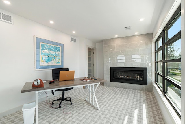 carpeted office featuring a tile fireplace and a wealth of natural light