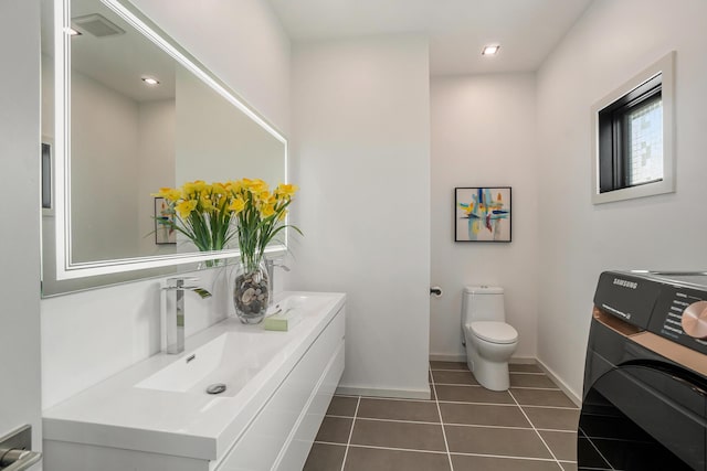 bathroom featuring tile patterned floors, toilet, vanity, and washer / dryer