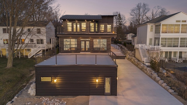 back house at dusk featuring a balcony and french doors