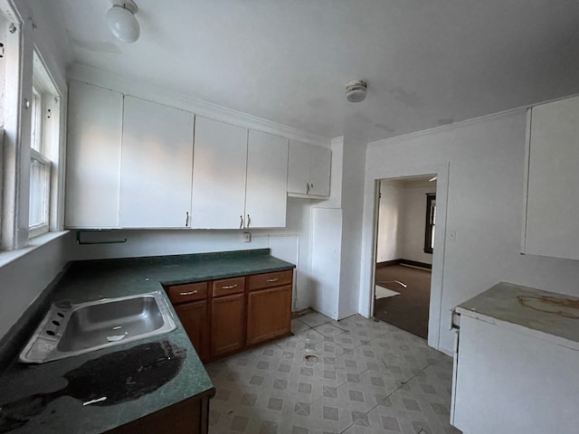 kitchen featuring white cabinets, ornamental molding, and sink