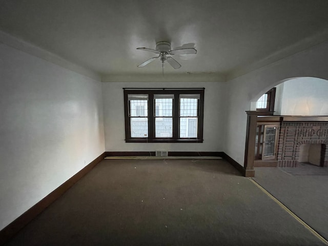 unfurnished living room featuring ceiling fan, a fireplace, carpet floors, and a healthy amount of sunlight