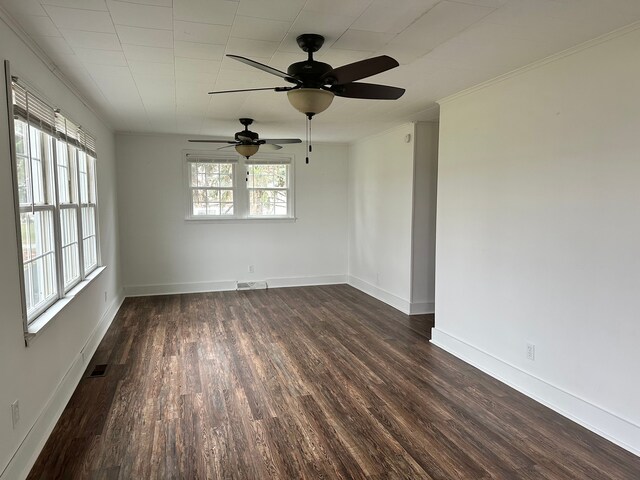 empty room featuring ceiling fan, plenty of natural light, ornamental molding, and dark hardwood / wood-style floors