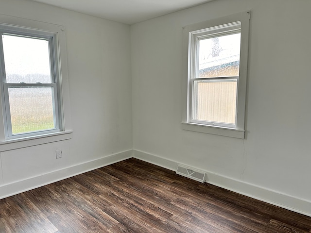 unfurnished room with dark wood-type flooring and plenty of natural light