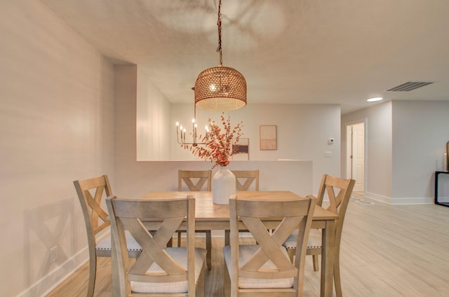 dining room with light hardwood / wood-style flooring and a notable chandelier