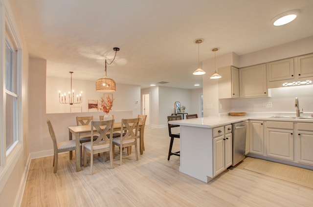 kitchen featuring stainless steel dishwasher, light wood-type flooring, kitchen peninsula, and hanging light fixtures