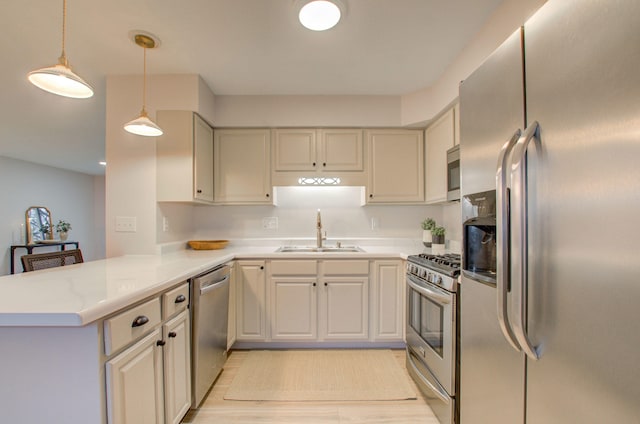 kitchen featuring sink, light hardwood / wood-style flooring, appliances with stainless steel finishes, decorative light fixtures, and kitchen peninsula