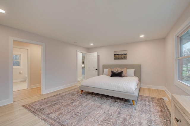 bedroom featuring connected bathroom and light hardwood / wood-style flooring