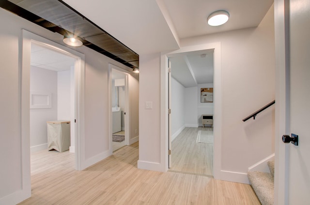 hall with light hardwood / wood-style floors and washer / clothes dryer