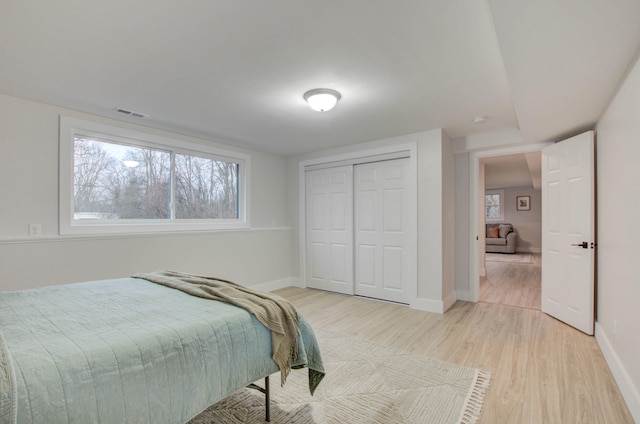 bedroom with light hardwood / wood-style floors and a closet