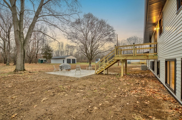 yard at dusk featuring central air condition unit, a patio, and a wooden deck