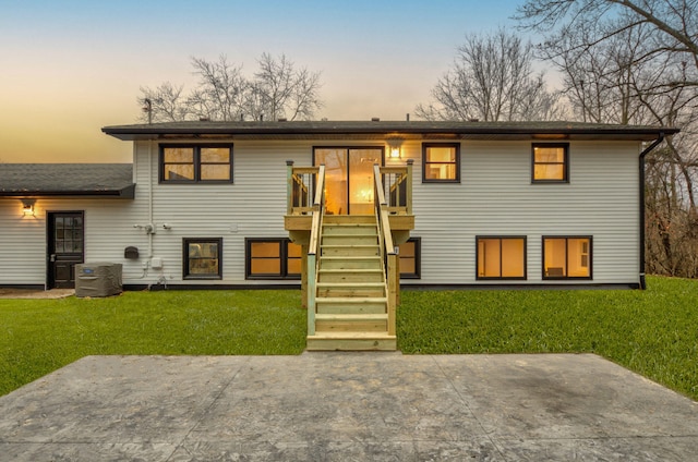 back house at dusk featuring a lawn, a patio area, cooling unit, and a wooden deck