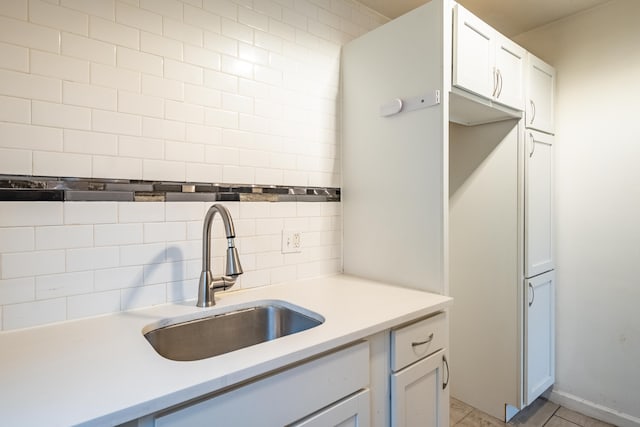 kitchen featuring white cabinets, decorative backsplash, light tile patterned floors, and sink