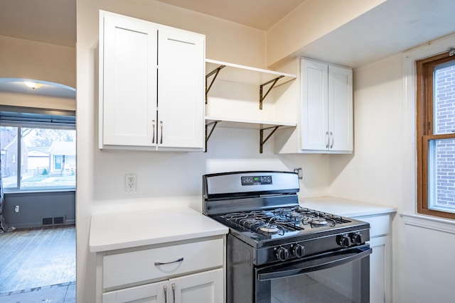 kitchen with white cabinets, gas stove, and light hardwood / wood-style flooring