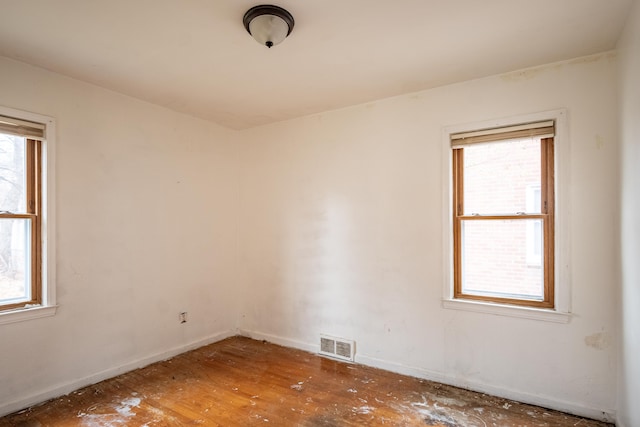 empty room featuring a healthy amount of sunlight and dark wood-type flooring