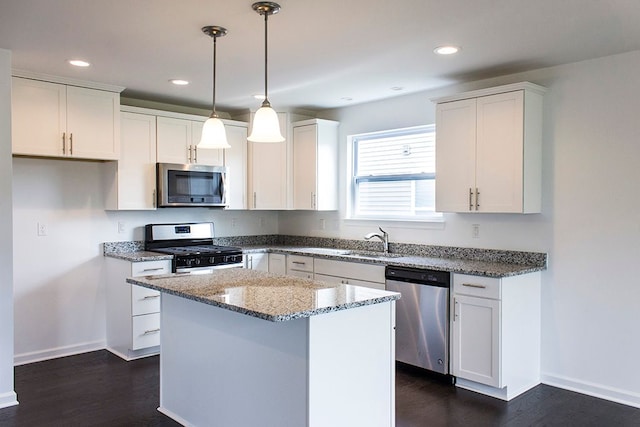 kitchen with a kitchen island, white cabinetry, hanging light fixtures, stainless steel appliances, and light stone counters